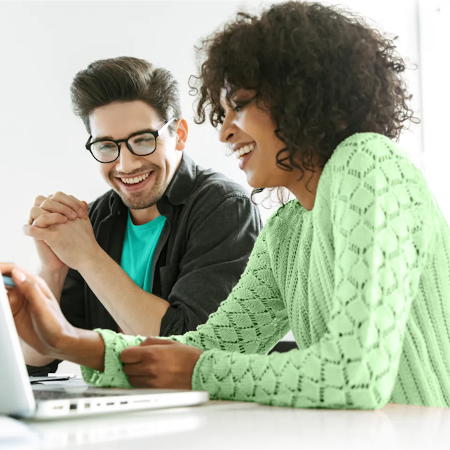 Homem e uma mulher, sorrindo e olhando para notebook