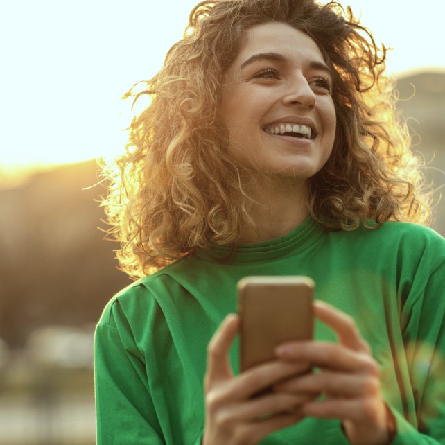 Mulher sorrindo e olhando o celular