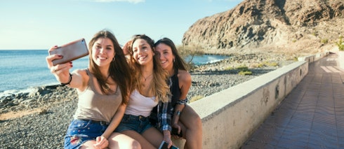 Amigas tirando selfie em frente à praia